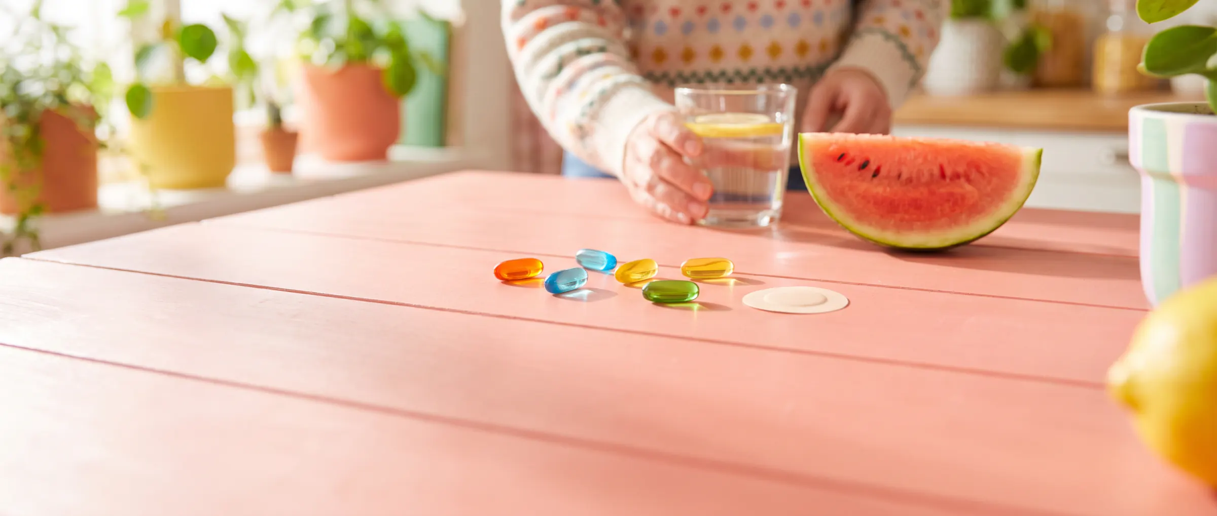 A few capsules and a small adhesive patch on a sunny pink table