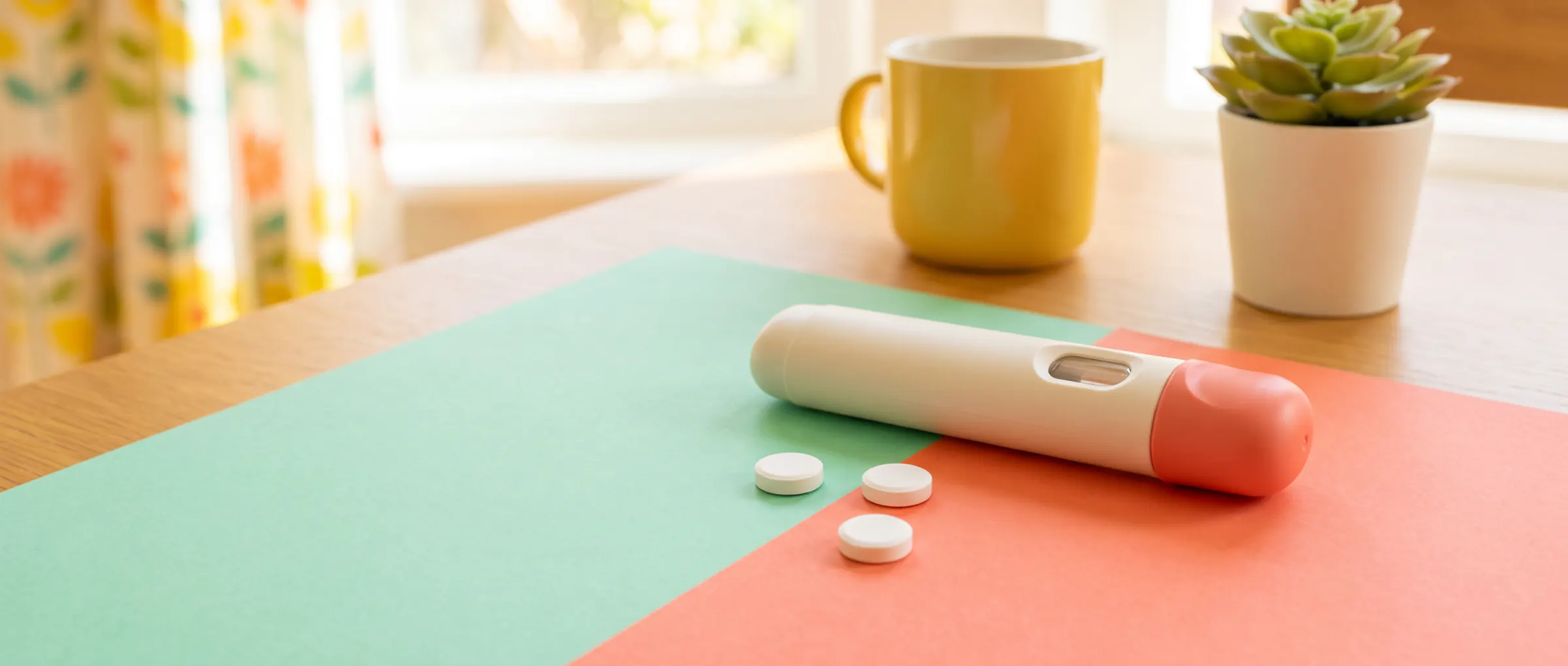 An injection pen next to a few tablets on a two-color table